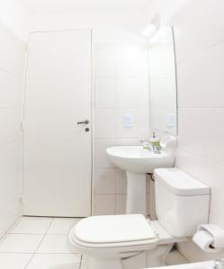 a white bathroom with a toilet and a sink at Cañada 2 dorm in Cordoba