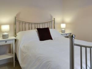 a bed with white sheets and a black pillow on it at Rose Cottage in Crocketford
