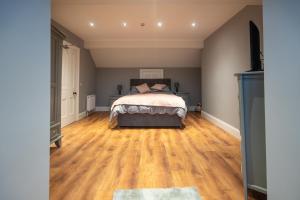 a bedroom with a bed and a wooden floor at The Bank Apartment Irvinestown in Irvinestown