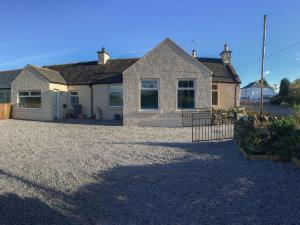 a house with a gravel driveway in front of it at Rose Cottage in Crocketford