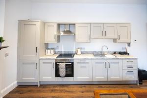 a kitchen with white cabinets and a sink at The Bank Apartment Irvinestown in Irvinestown