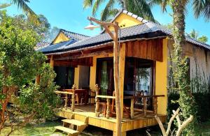 uma pequena casa amarela com um alpendre e uma mesa em Dugong Resort Phu Quoc em Phu Quoc