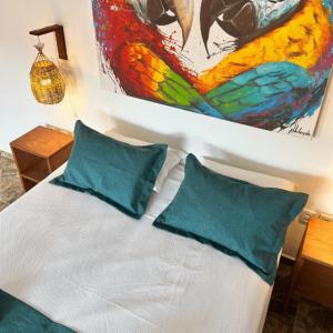 uma cama com duas almofadas e um quadro na parede em Pousada Oasis em Pipa