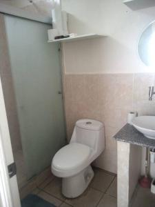 a bathroom with a white toilet and a sink at El Hostal 57 in San Juan Opico