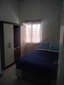 um quarto com uma cama azul e uma janela em El Hostal 57 em San Juan Opico