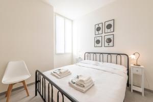a white bedroom with a bed and a chair at Maloja, 10 – Casa Maloja – ampio appartamento in Milan