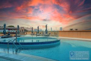 a large swimming pool with a sunset in the background at Capital Stay - 2 Bed Apartment in Dubai Festival City in Dubai