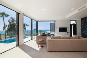 sala de estar con sofá, TV y puertas de cristal en 200m² NEW Villa F with private, heated pool and amazing ocean view., en Adeje