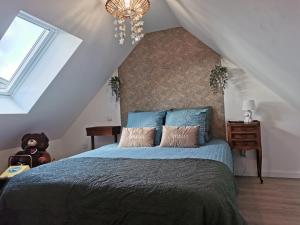 Un dormitorio con una cama con sábanas azules y una lámpara de araña. en Les gîtes de L'hermine, en Plouigneau