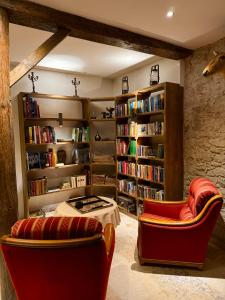 eine Bibliothek mit 2 Stühlen, einem Tisch und Bücherregalen in der Unterkunft Pax et Amor Chambres d'hôtes de charme - Charming B&B in Mazerolles-du-Razès