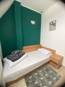 een kleine slaapkamer met een bed en een groene muur bij HOTEL MILO - Noclegi Bartoszyce in Bartoszyce