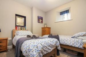 1 dormitorio con 2 camas y espejo en West Lodge Cottage en Morpeth