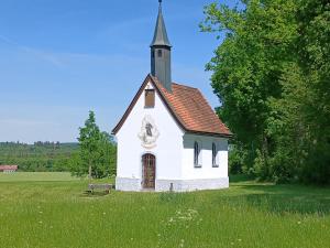 a small white church with a steeple in a field at Ferienwohnung Oberlinner in Miesbach