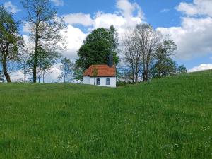 une petite maison au sommet d'une colline herbeuse dans l'établissement Ferienwohnung Oberlinner, à Miesbach