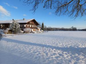 een huis in de sneeuw voor een veld bij Ferienwohnung Oberlinner in Miesbach