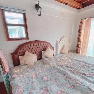 a bedroom with a large bed with a floral bedspread at 猫とピアノと星空のリゾートブティックコテージ - Starry Forest Cottage Okinawa - in Onna