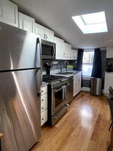 una cocina con nevera de acero inoxidable y armarios blancos en Large studio apartment steps from the US Capitol!, en Washington