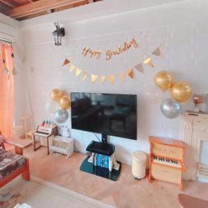 een woonkamer met een flatscreen-tv en ballonnen bij 猫とピアノと星空のリゾートブティックコテージ - Starry Forest Cottage Okinawa - in Onna