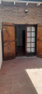 a garage with two wooden doors and a brick wall at Casa alquiler temporario Necochea in Necochea