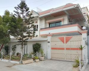 a white house with a gate and a fence at Travel lodge clifton in Karachi