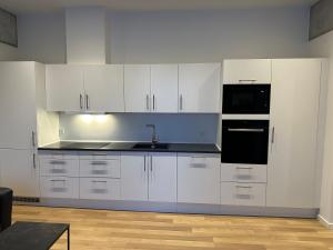 a kitchen with white cabinets and a black appliance at City apartment Dæmningen Vejle in Vejle