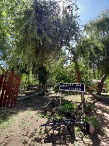 un cartel frente a un jardín con árboles en Complejo de Cabañas Estancia Del Águila en Mina Clavero