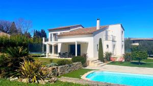 a white house with a swimming pool in front of it at Villa des Chardonnerets in Mougins