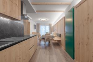 eine Küche mit Holzschränken und einem Tisch mit grüner Tür in der Unterkunft Appartamenti Residence Ada in St. Kassian