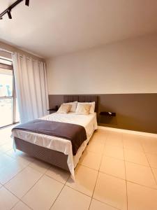 a bedroom with a bed and a large window at Excutive apartamentos in Joinville