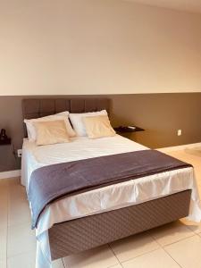 a bedroom with a large bed with white sheets and pillows at Excutive apartamentos in Joinville