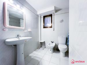 La salle de bains blanche est pourvue d'un lavabo et de toilettes. dans l'établissement Estiloso Apto en P. Marítimo, à Oropesa del Mar