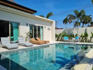 a swimming pool with chairs and a house at La Ville Phuket Pool Villa in Nai Yang Beach