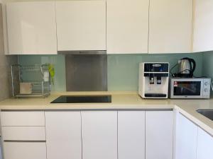 a kitchen with white cabinets and a sink and a microwave at AFINITI-Legoland-walk5min CottonSheep 2RB Max8pax Bathtub in Nusajaya
