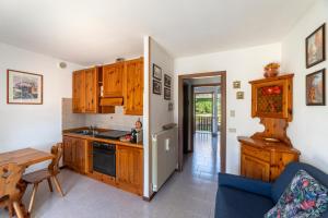 a kitchen with wooden cabinets and a table and a blue couch at Villetta a schiera con giardino privato in Castione della Presolana