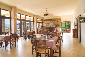 a dining room with tables and chairs and windows at Melidoni X Village in Melidhónion