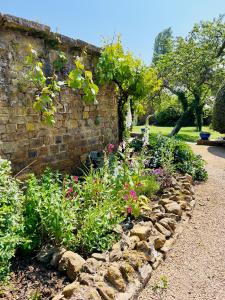 um jardim com flores e uma parede de tijolos em Large room in Stunning Cottage Edge of the Cotswolds em Bloxham