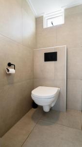 een badkamer met een wit toilet en een raam bij Duinhuysje in Domburg