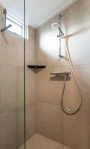 een douche met een glazen deur in de badkamer bij Duinhuysje in Domburg