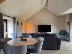 a living room with a couch and a table and chairs at Ambiance boisée Moustier in Stoumont