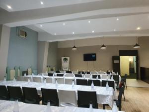 una sala de conferencias con mesas y sillas blancas en Indaba Hotel - Sasolburg en Sasolburg