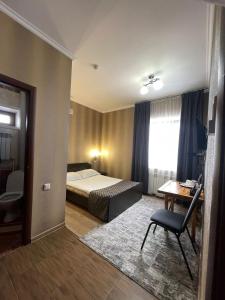 a bedroom with a bed and a desk and a chair at VIP Mini Hotel in Semey