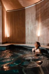 een vrouw in een bubbelbad in een hotelkamer bij BOTANIQ Castle of Tura - Small Luxury Hotels of the World in Tura