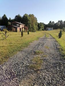 uma estrada de cascalho num campo com uma casa ao fundo em Piso acogedor y familiar en el campo em Villarrica