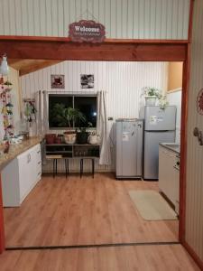 a kitchen with white appliances and a wooden floor at Piso acogedor y familiar en el campo in Villarrica