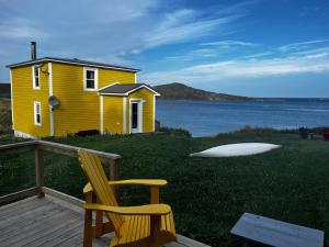 una casa amarilla con una silla y un lago en Petals oceanview villa, 