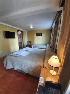 um quarto de hotel com 2 camas e uma secretária com telefone em Monte Cervino Hotel em San Carlos de Bariloche