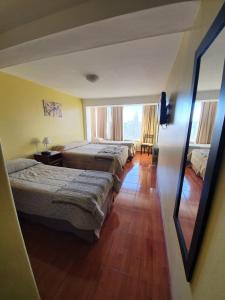 um quarto de hotel com três camas e uma janela em Monte Cervino Hotel em San Carlos de Bariloche