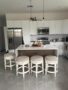 una cocina con una isla con tres taburetes y un mostrador en The Lake House, en Fort Lauderdale