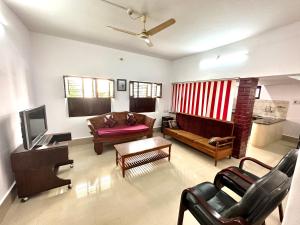 een woonkamer met een bank en een tv bij Malgudi House - Viceroy in Mysore