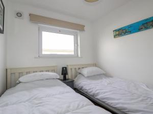 two beds in a room with a window at Lapwing in Perranporth